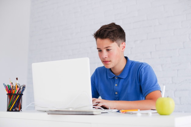 Serious guy studying with laptop at desk