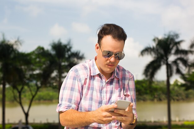 Serious guy texting sms on smartphone while walking outdoors