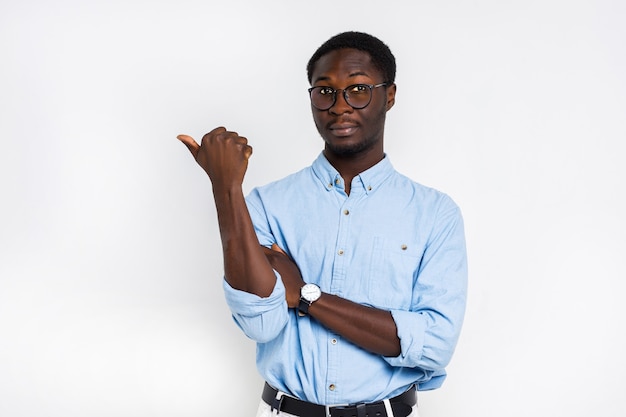 Free photo serious handsome man in glasses points with his finger on isolated white wall