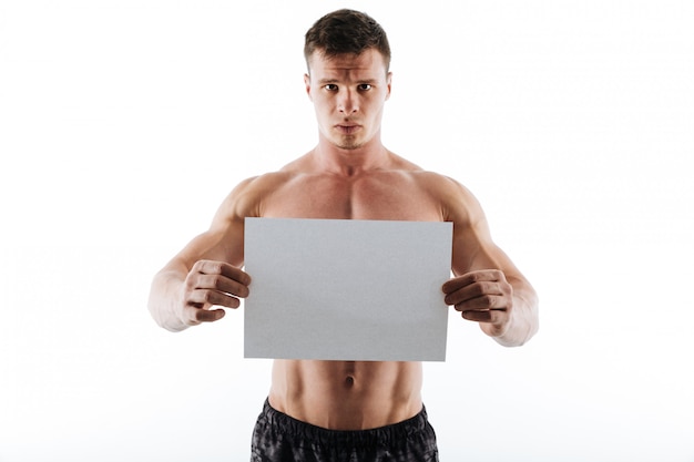 Serious handsome young sportsman holding copyspace paper