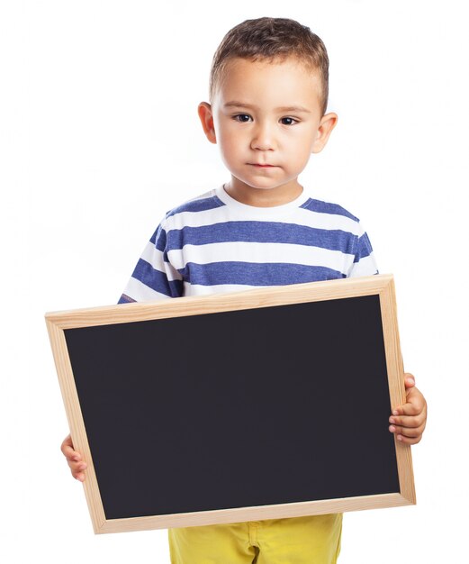 Serious little boy holding a blackboard