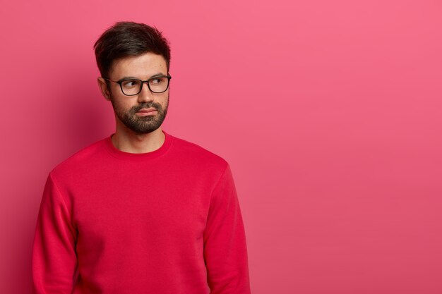 Serious looking bearded man looks aside with thoughtful expression