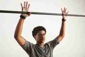 Free photo serious looking black gymnast in gray tshirt and gymnastics hand protection preparing to grab a black carbon pullup bar, fingers outstretched, isolated on white