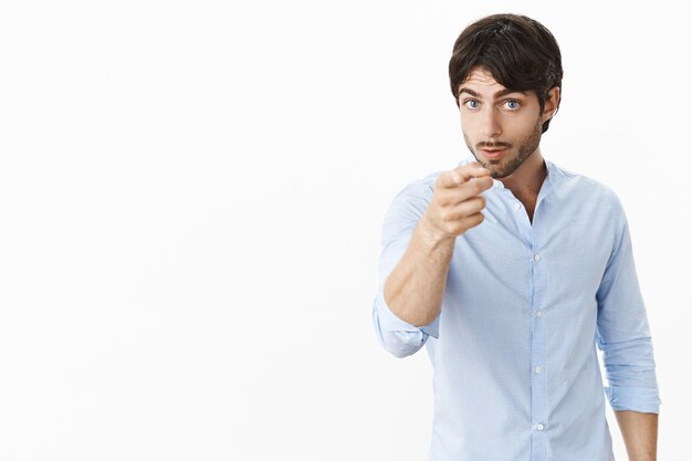 Serious-looking bossy and displeased attractive male entrepreneur in shirt looking, pointing at front as displeased with unproductive work warning employee he might be fired