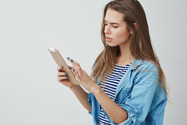 Serious-looking busy attractive young successful woman using digital tablet