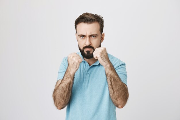 Serious-looking pissed-off man raising fists to fight