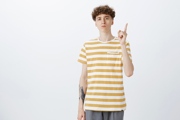 Serious-looking teenage guy posing against the white wall