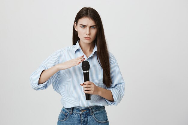 Serious-looking woman checking microphone