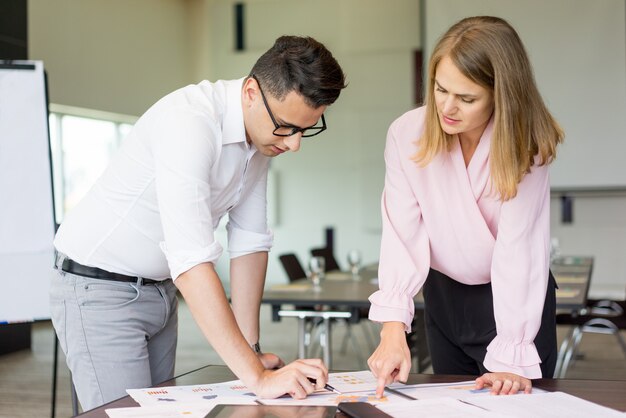 Serious male and female colleagues working with statistic documents. 