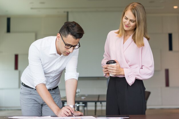 Serious male manager showing project to female executive.