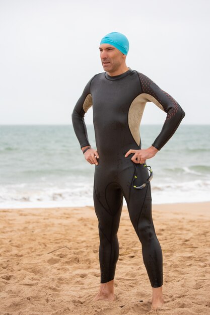 Serious male swimmer standing on beach