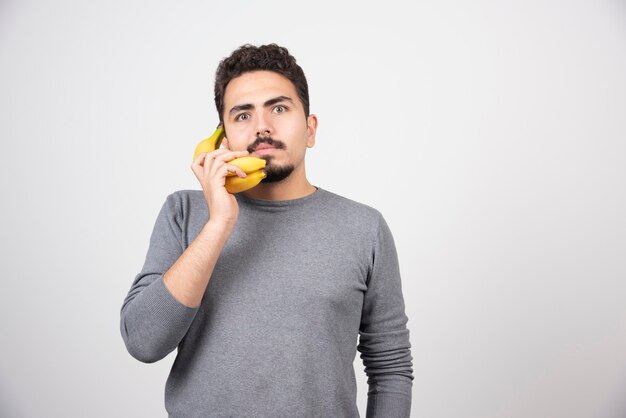 Serious male talking with banana on gray.