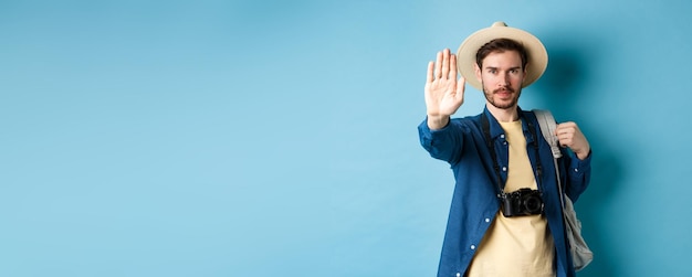 Free photo serious male tourist warn you stretch out hand to show stop gesture man on vacation forbid something