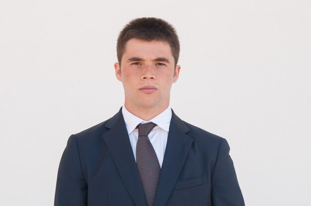 Serious man in formal jacket and tie standing for camera