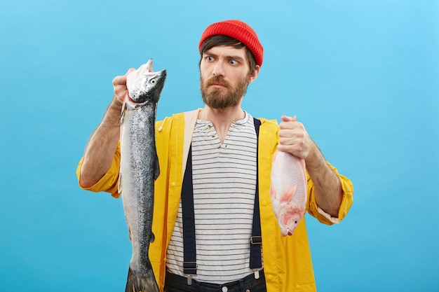 Serious man holding two fish looking at his catch