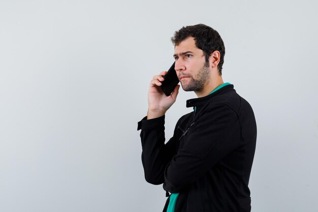 The serious man is talking with phone on white background