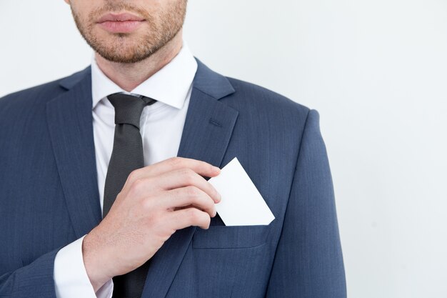Serious man putting business card into pocket