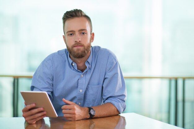 Serious Man Sitting at Cafe Table with Tablet