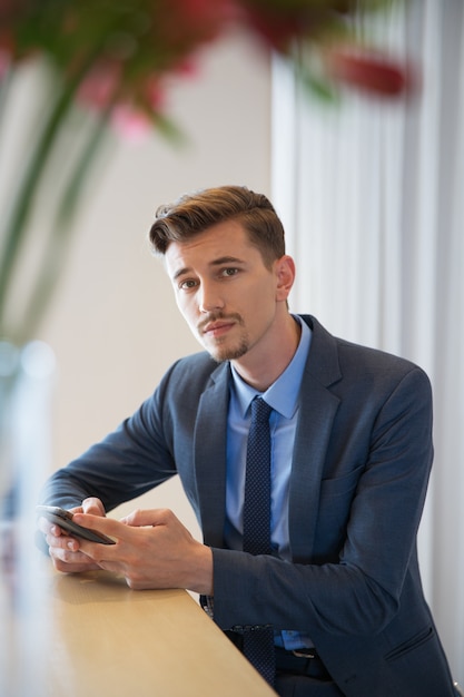 Serious Man with Smartphone Sitting in Cafe