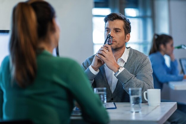 Serious manager communicating with his female employee on a meeting in the office