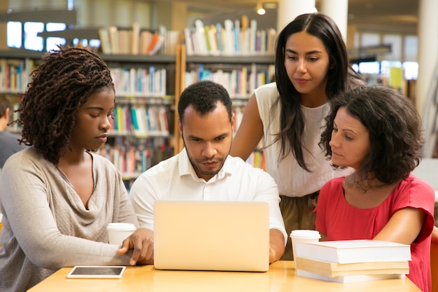 Serious mature students working with laptop at public library