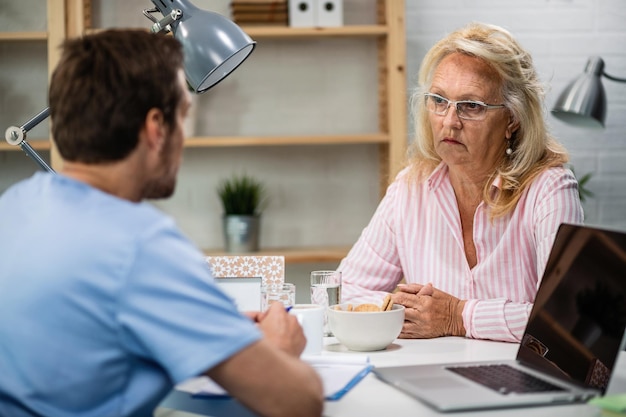 Serious mature woman talking with doctor after medical exam at doctor's office