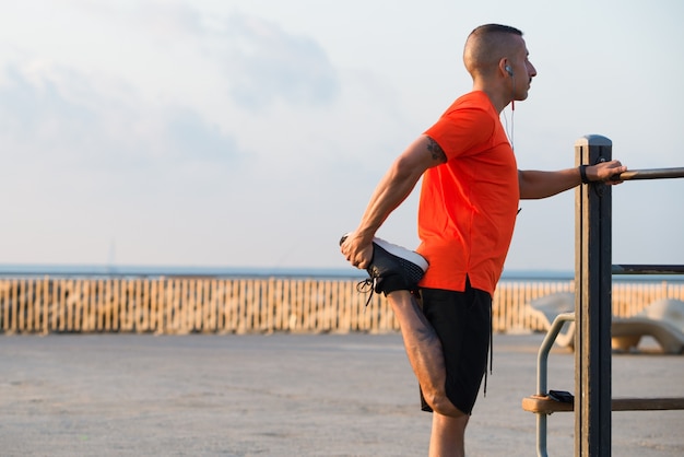 Serious mid adult male athlete stretching leg