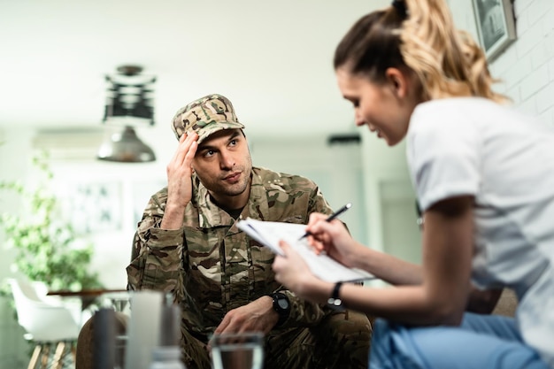 Serious military man communicating with female doctor who is visiting him at home