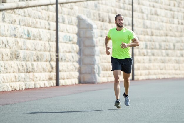 道路上で走っている筋肉質のスポーティな男