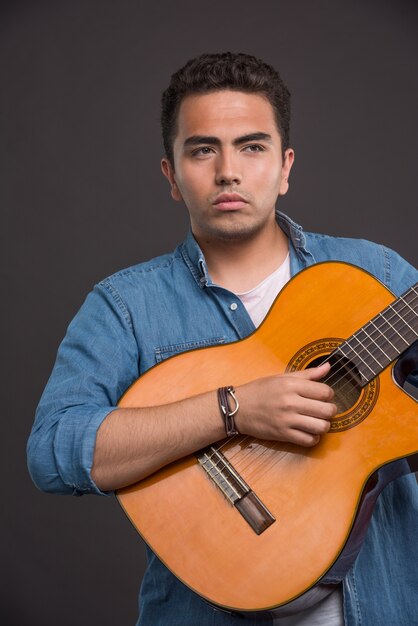 Serious musician playing the guitar on black background