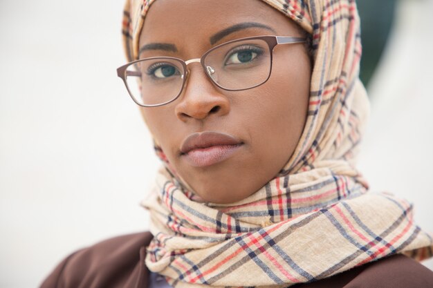 Serious Muslim woman in glasses posing outside