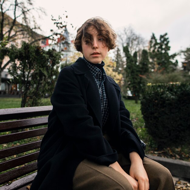 Serious non binary person sitting on a bench