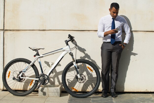 Free photo serious office worker near bike reading message