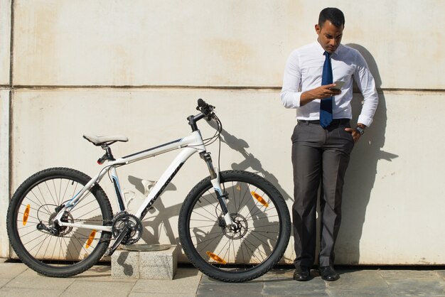 Серьезный офисный работник возле сообщения для чтения велосипедов