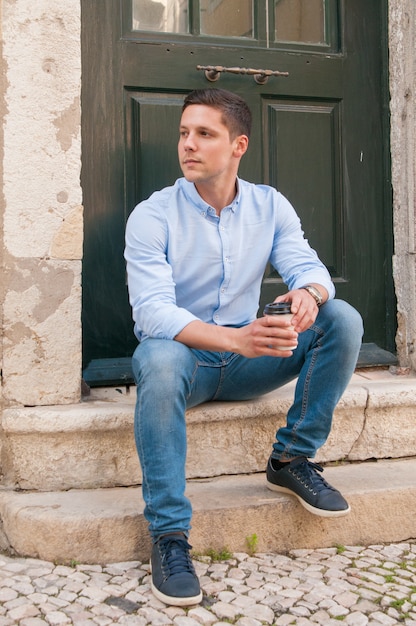 Serious pensive guy drinking takeaway coffee