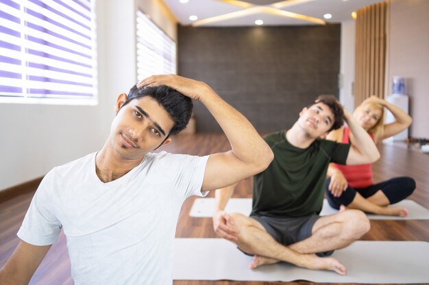 Серьезные люди, растягивающие шею в классе йоги