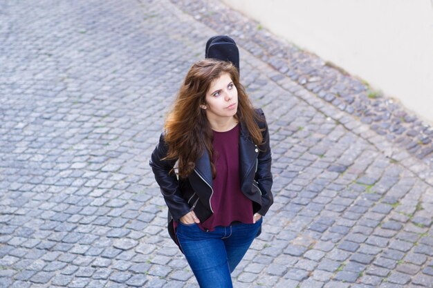 Serious Pretty Woman Walking with Guitar on Street