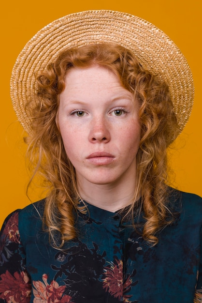 色付きの背景のスタジオで深刻な赤毛の女性