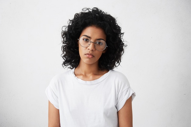 Serious and sad black woman with Afro haircut wearing big elegant glasses