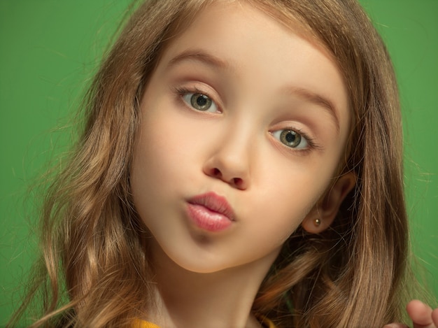 Serious, sad, doubtful, thoughtful teen girl standing at green studio