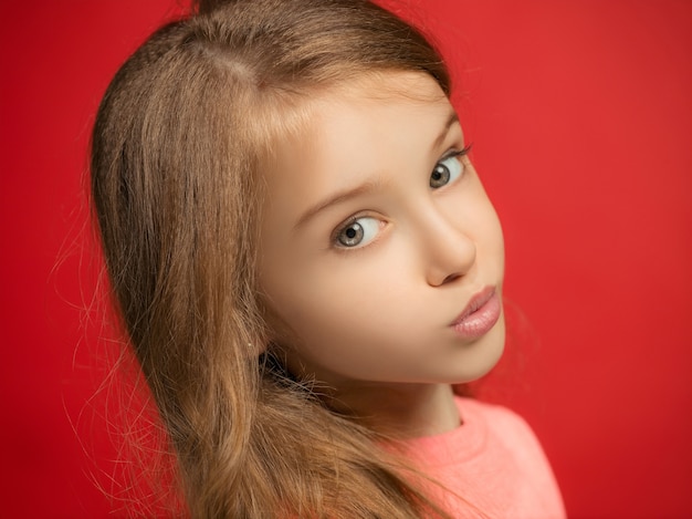 Serious, sad, doubtful, thoughtful teen girl standing at red studio