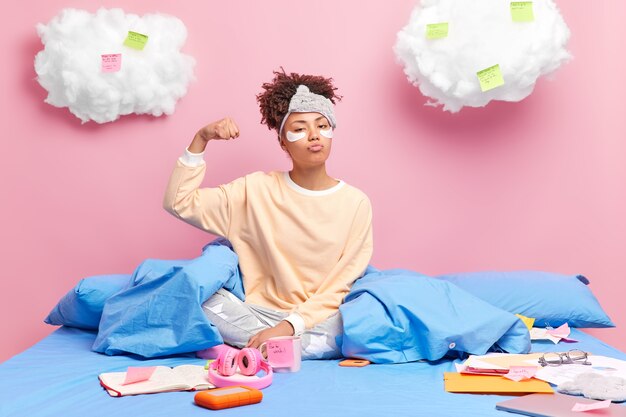 Serious self confident African American millennial girl raises arm and shows biceps being proud