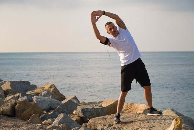 Serious sportsman doing exercising on shore