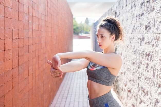 Serious Sporty Girl Stretching Arms Between Walls