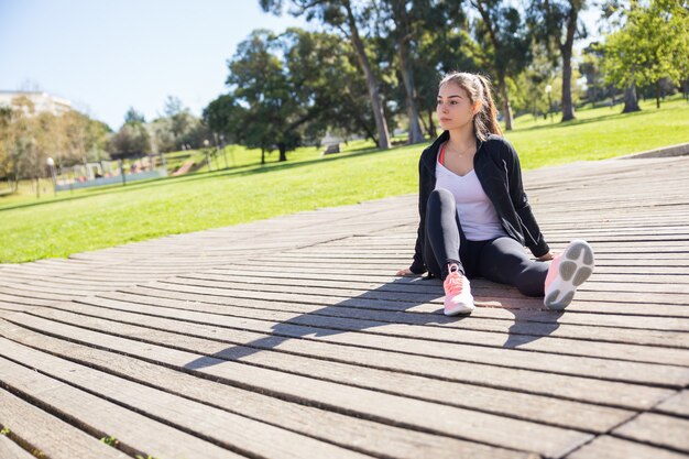 Serious sporty lady relaxing outdoors