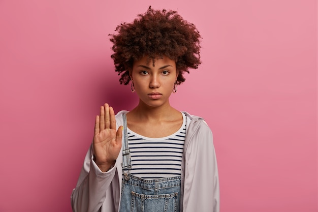 Free photo serious strict woman shows stop gesture, raises palm forward