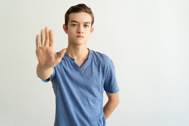 Serious strict young man making restriction gesture