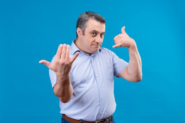 Serious and strictconfident man with angry expression demanding person step forward on a blue background