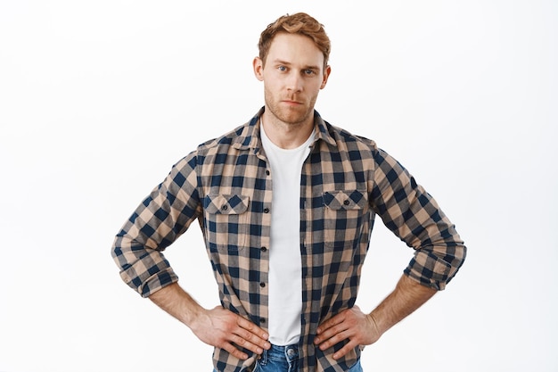 Free photo serious strong guy with red hair, standing in waiting pose, looking judgemental, wait for explanation, scolding someone, posing confident against white background