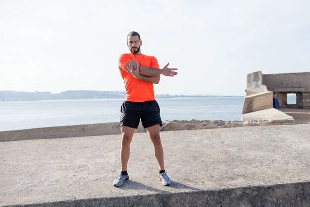 Serious Strong Sporty Man Stretching Arm Outdoors